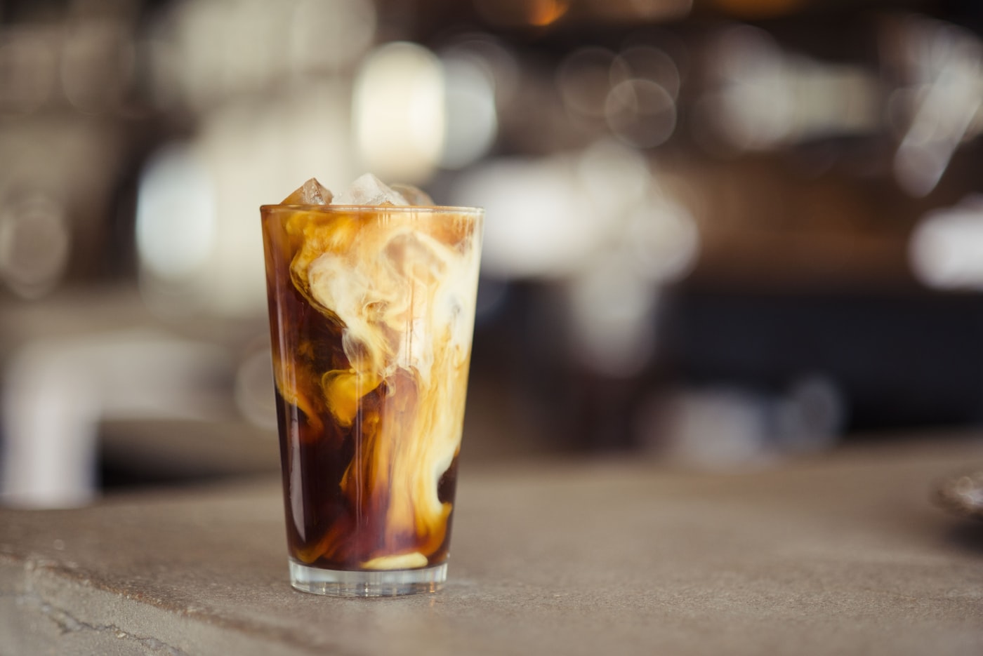 Iced kopi susu in a tall glass on a wooden table