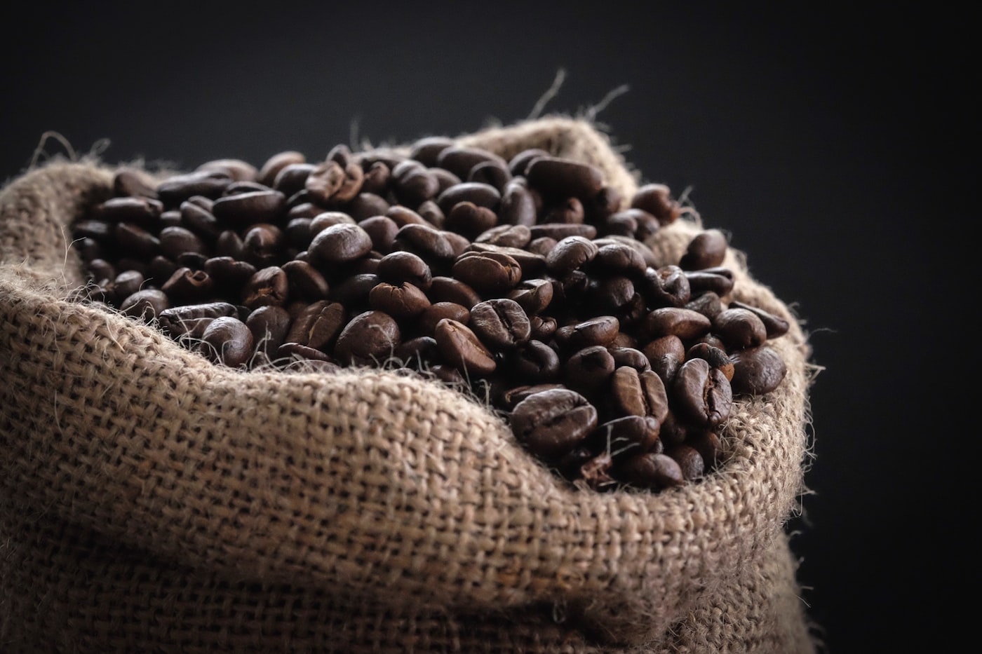 A scoop of roasted beans beside a paper coffee bag