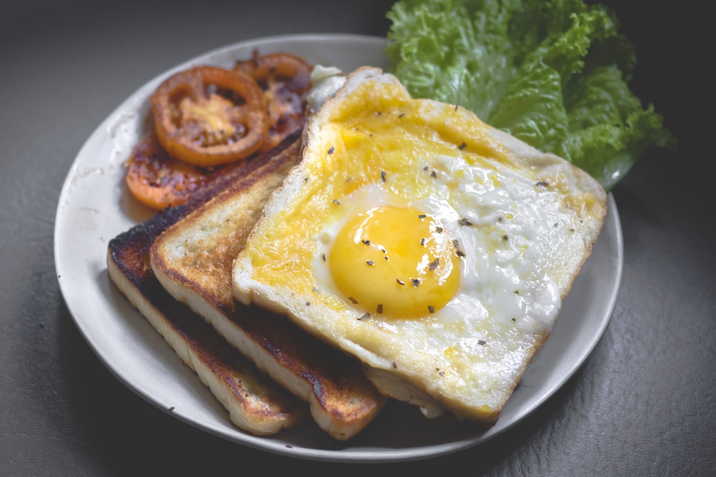 A loaded breakfast plate with eggs, sausage, mushrooms, greens and sourdough